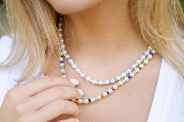 A young college student wearing beaded choker necklaces with blue, pearl, and multicolor beads