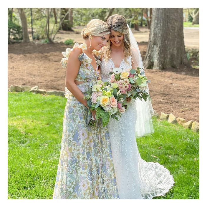 bride and bridesmaid posing together outside with large flower bouquets