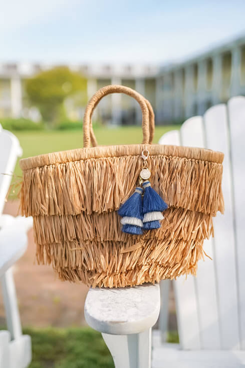 handwoven straw purse sitting on white adirondack chair