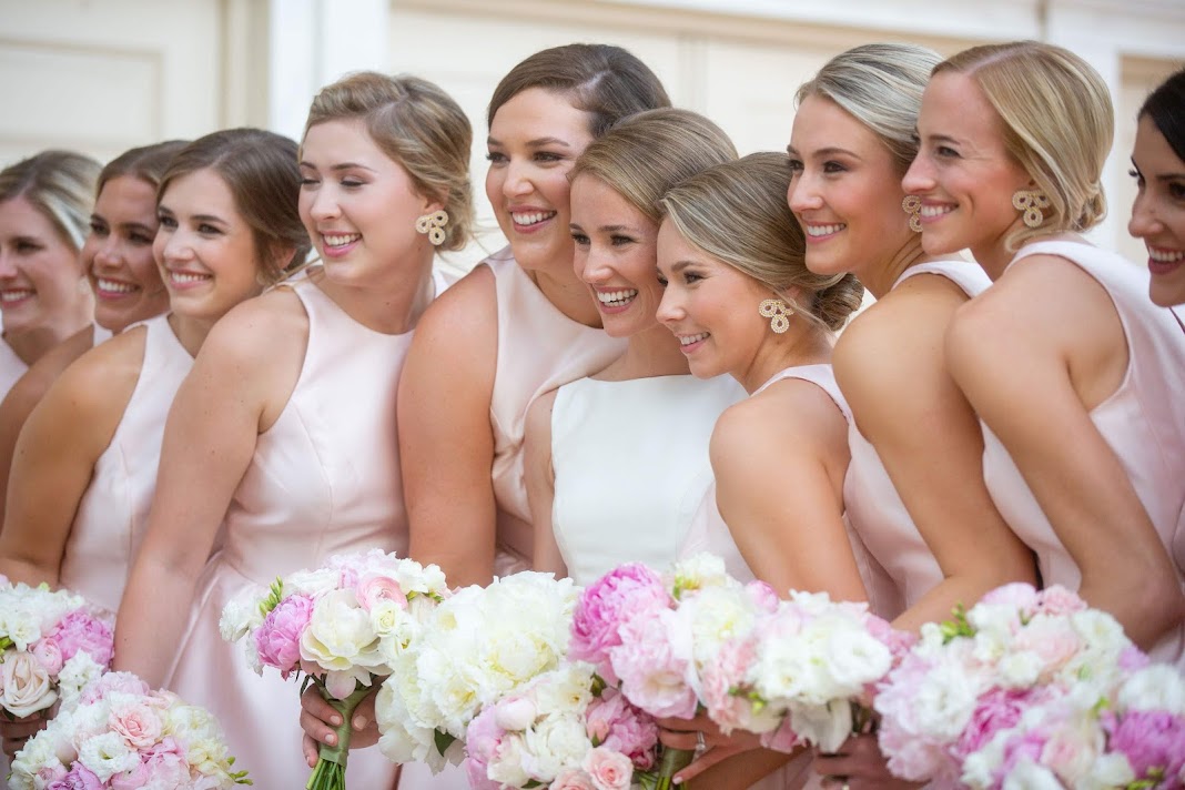 bride and bridesmaids holding pink and white bouquets and wearing beaded earrings